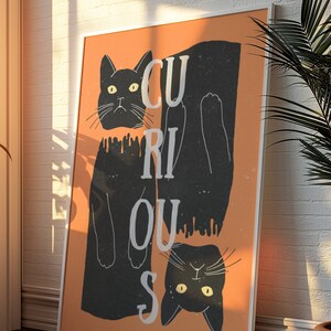 May include: A framed print with an orange background and two black cats. The cats are upside down and the word "CURIOUS" is written vertically in white letters.