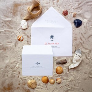 May include: Two white envelopes with handwritten addresses on a sandy beach background. The top envelope has a palm tree icon and the text "Mr Elizabeth Elliot, DOD LANE, IRE ENGLAND". The bottom envelope has a fish icon and the text "505 MULBERRY AVE, SOMERSETSHIRE, ENGLAND".