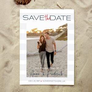 Puede incluir: Tarjeta de Save the Date con fondo a rayas azul y blanco. Una foto de una pareja caminando por la playa al atardecer está en el centro de la tarjeta. El texto "SAVE the DATE" está en la parte superior de la tarjeta en azul y rojo. El texto "FOR THE WEDDING OF Anne & Frederick" está debajo de la foto en azul. La fecha "DEC 20, 1887" y la ubicación "SOMERSETSHIRE, UK" están en la parte inferior de la tarjeta.