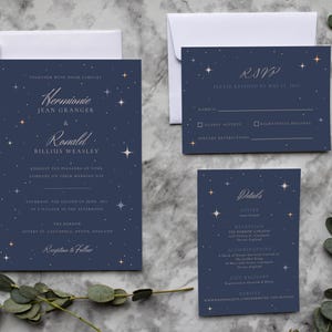 May include: Navy blue wedding invitation suite with a celestial theme. The invitation, RSVP, and details cards feature starry accents and elegant typography. The invitation includes the names "Hermione" and "Ronald".
