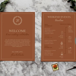 May include: A brown wedding invitation with a gold wreath and the text "Welcome to our wedding celebration". The invitation also includes a timeline of events for the wedding weekend.