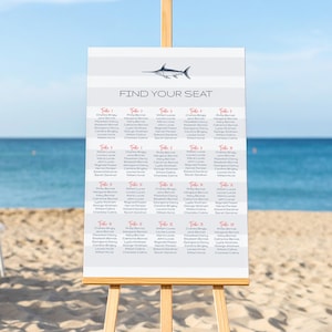 May include: A white and grey striped seating chart with a black and white illustration of a swordfish. The chart has the words "Find Your Seat" in black text. The chart lists the names of guests for each table number.