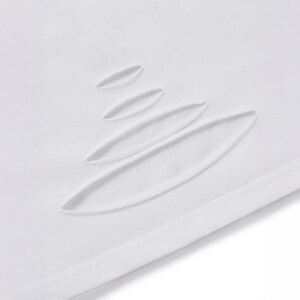 May include: Close-up of white fabric featuring several elongated, oval cut-outs. These are arranged diagonally, creating a textured effect. The fabric has a smooth, clean appearance, with a visible seam at the edge.