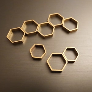May include: A set of nine gold-toned metal hexagonal rings of varying sizes. The rings are arranged in a honeycomb pattern.