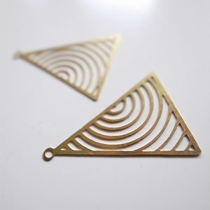 May include: Two gold triangle-shaped earrings with a geometric pattern of concentric circles.