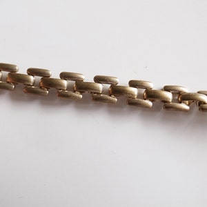 Puede incluir: Un brazalete de cadena de metal dorado con un diseño de eslabones.