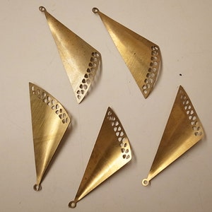 Può includere: Sei ciondoli triangolari in metallo color oro con tagli decorativi. I ciondoli hanno un foro nella parte superiore per essere appesi.