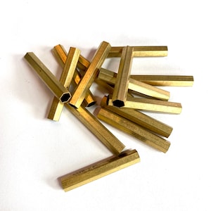 May include: A group of brass hexagonal tubes, some are straight and some are bent into a U shape.