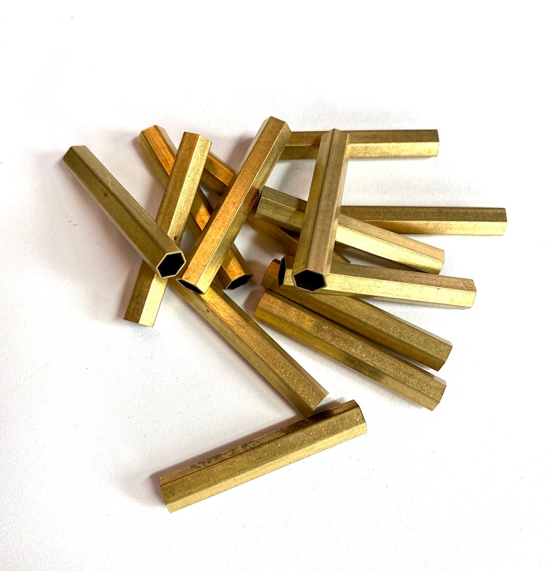 May include: A group of brass hexagonal tubes, some are straight and some are bent into a U shape.