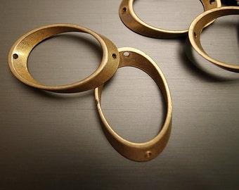 May include: Four gold-colored metal rings, each with a circular shape and a smooth, polished finish. The rings are arranged in a loose pile, with some overlapping.