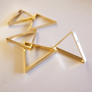 May include: Four gold-coloured triangle-shaped rings stacked on top of each other.