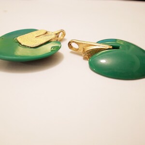 Puede incluir: Dos colgantes en forma de coraz&oacute;n verde con detalles dorados. Los colgantes tienen un acabado brillante y lustroso.