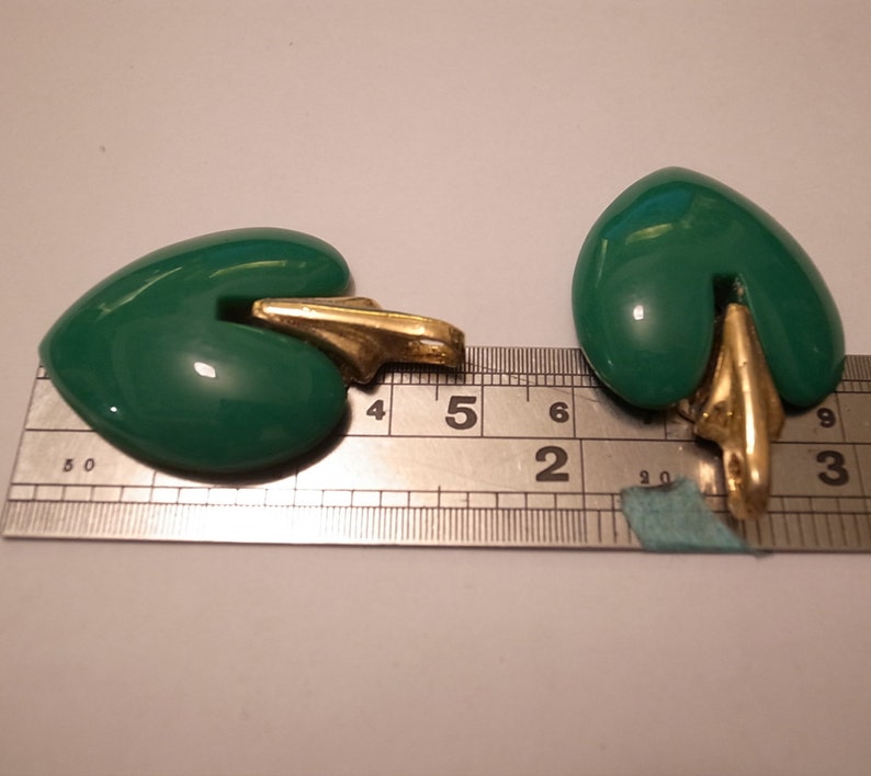 Puede incluir: Dos colgantes en forma de coraz&oacute;n verde con bucles de metal dorado. Los colgantes miden aproximadamente 3,8 cm de largo y se miden con una regla.