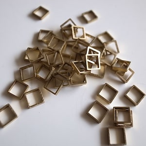 30 piezas de abalorios de tubo de latón crudo recién cortados en una pequeña caja cuadrada con forma geométrica de cubo 3D de 5,5 x 5,5 x 1,2 mm.
