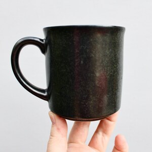 Pu&ograve; includere: Una tazza in ceramica nera con una glassa macchiettata.