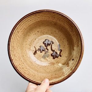 Może przedstawiać: Brązowa ceramiczna miska z pstrokatą glazurą i brązowym wzorem kwiatowym.