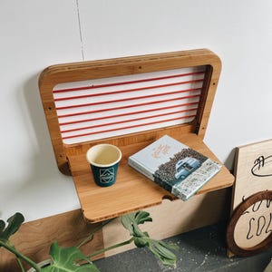 May include: A white ceramic mug with a black handle and the text "But First, Coffee" in a bold, black font. The mug is set against a blurred background, suggesting a cozy setting. The mug appears to be approximately 4 inches tall.