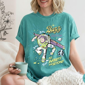 Peut inclure: Une tasse en c&eacute;ramique blanche avec une anse noire et le texte "But First, Coffee" en gras noir. La tasse est pos&eacute;e sur un fond flou, soulignant son design &eacute;pur&eacute;.