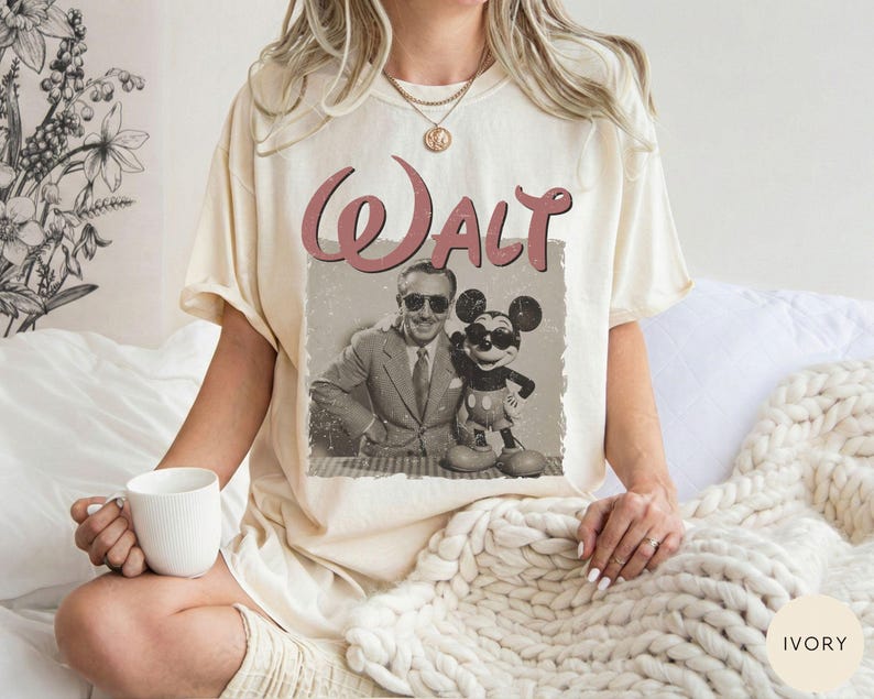 Puede incluir: Camiseta color marfil con un gr&aacute;fico vintage de Walt Disney y Mickey Mouse. La palabra "Walt" est&aacute; impresa en una fuente cursiva roja encima de la imagen. La camiseta tiene un corte holgado y mangas cortas.