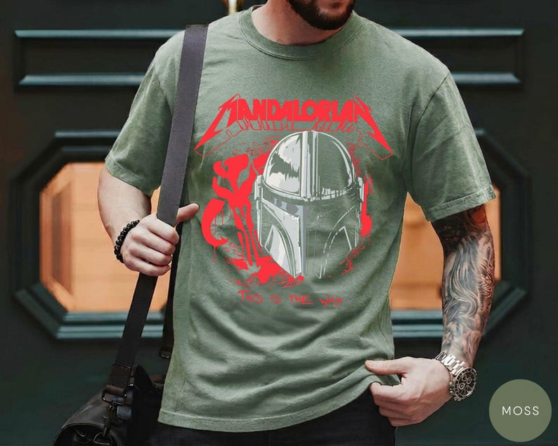 Op de afbeelding: Mosgroen t-shirt met een afbeelding van een Mandalorian helm en de woorden "Mandalorian" en "Way of the Jedi" in het rood. Het t-shirt heeft een ronde hals.