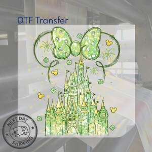 K&ouml;nnte beinhalten: Ein gr&uuml;n-gelbes Schlossdesign mit einer Schleife und Mickey Mouse-Symbolen. Das Bild enth&auml;lt den Text "DTF Transfer" und ein "Next Day Shipping"-Logo. Das Schloss hat mehrere T&uuml;rme und Flaggen, mit einem skurrilen, handgezeichneten Stil.