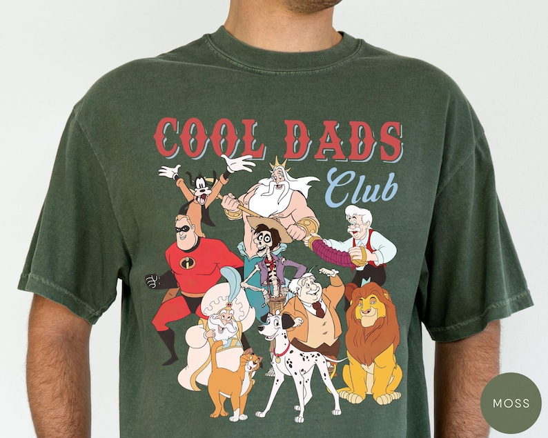 May include: Moss green t-shirt featuring a graphic of various cartoon characters with the text "COOL DADS Club" in red and white. The design includes characters like Mr. Incredible, Simba, and Goofy.