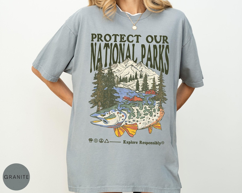 May include: A light blue t-shirt with the text "PROTECT OUR NATIONAL PARKS" above a graphic of a mountain range, trees, and a fish. The phrase "Explore Responsibly" is below the graphic.
