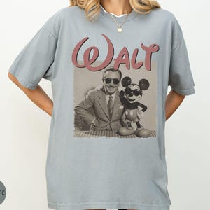 Puede incluir: Camiseta azul claro con un gr&aacute;fico retro de Walt Disney y Mickey Mouse. La palabra "Walt" est&aacute; impresa en una escritura granate sobre la imagen. La camiseta tiene un corte holgado y mangas cortas.