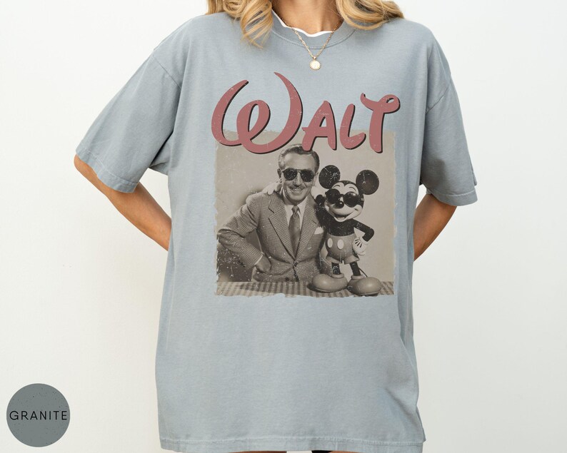 Puede incluir: Camiseta azul claro con un gr&aacute;fico retro de Walt Disney y Mickey Mouse. La palabra "Walt" est&aacute; impresa en una escritura granate sobre la imagen. La camiseta tiene un corte holgado y mangas cortas.