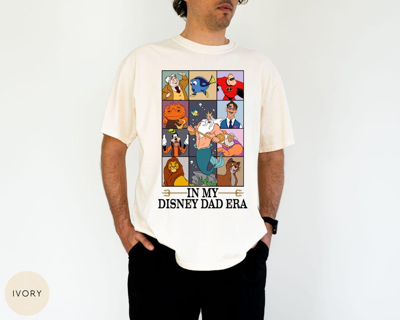 May include: Ivory-colored t-shirt featuring a grid of Disney character illustrations. The shirt includes characters like Dory, Mr. Incredible, and Simba. Text on the shirt reads "IN MY DISNEY DAD ERA."