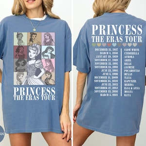May include: Blue jean-colored t-shirt featuring a graphic of Disney princesses in a grid, with the text "PRINCESS THE ERAS TOUR." The back of the shirt lists tour dates and princess names. A casual, oversized fit.