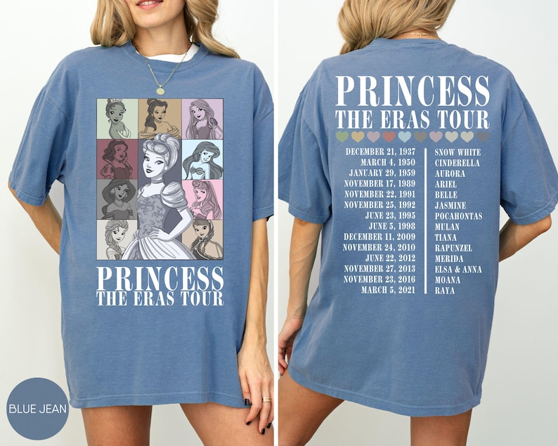 May include: Blue jean-colored t-shirt featuring a graphic of Disney princesses in a grid, with the text "PRINCESS THE ERAS TOUR." The back of the shirt lists tour dates and princess names. A casual, oversized fit.