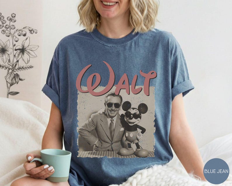Puede incluir: Camiseta azul vaquero con un gr&aacute;fico de estilo vintage de Walt Disney con Mickey Mouse. La palabra "Walt" est&aacute; en escritura rosa encima de la imagen. La camiseta tiene las mangas enrolladas.