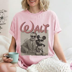 Puede incluir: Camiseta rosa claro con un gr&aacute;fico vintage de Walt Disney y Mickey Mouse. La palabra "Walt" est&aacute; impresa en una fuente retro encima de la imagen. La camiseta es de color rosa claro.