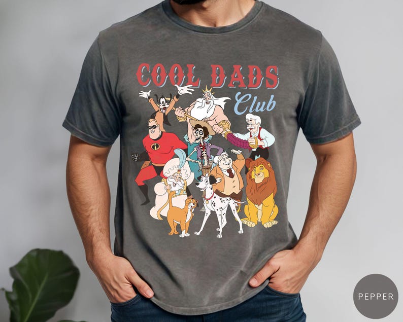 May include: Dark gray t-shirt featuring a graphic of cartoon characters with the text "COOL DADS Club" in red and blue. The shirt has a vintage, faded look and a crew neck.