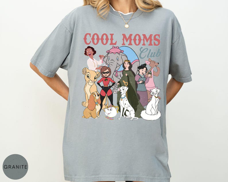 May include: A light gray t-shirt with the text "COOL MOMS Club" in red and blue. The shirt features a graphic of cartoon characters, including a lion cub, a dog, and a cat.