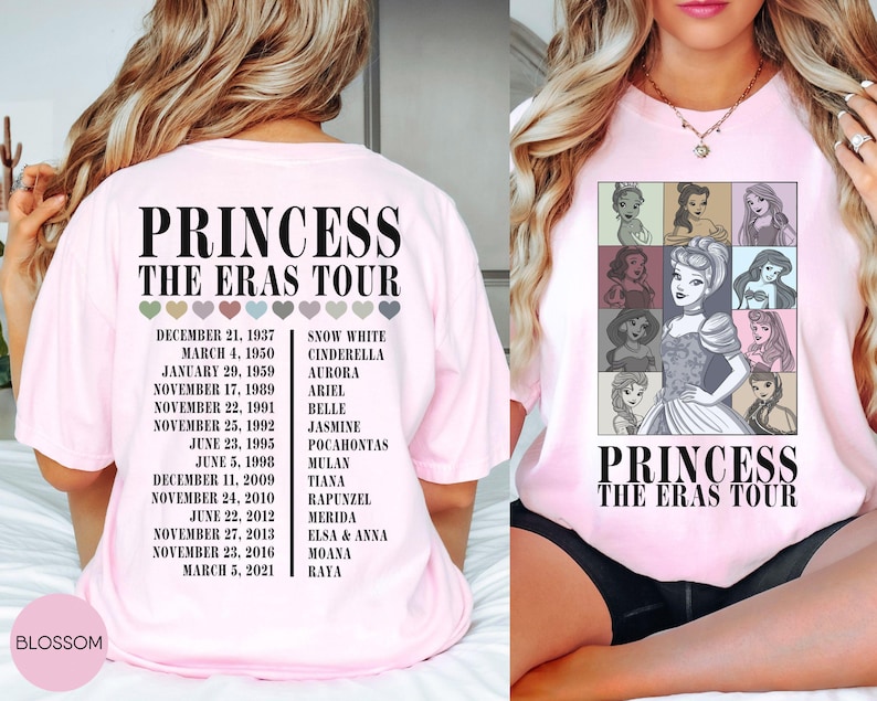May include: Light pink t-shirt featuring a graphic of Disney princesses in a grid, with the text "PRINCESS THE ERAS TOUR". The back of the shirt lists dates and princess names. A Blossom logo is visible.