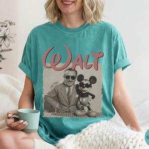 Puede incluir: Camiseta verde mar con un gr&aacute;fico vintage de Walt Disney y Mickey Mouse. El gr&aacute;fico incluye el nombre "Walt" en escritura rosa. La imagen de Walt Disney y Mickey Mouse es en blanco y negro.