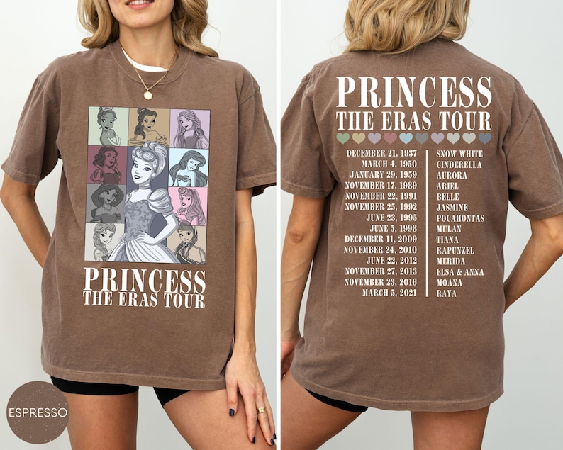May include: Espresso-colored t-shirt featuring a graphic of Disney princesses and the text "PRINCESS THE ERAS TOUR." The front displays princess portraits. The back lists princess names and tour dates. A casual, comfortable tee.