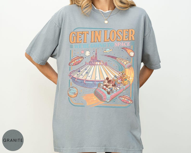Pode incluir: Camiseta cinza claro com um gr&aacute;fico de um passeio tem&aacute;tico espacial. O design inclui o texto "GET IN LOSER WE'RE GOING TO SPACE" em laranja e azul, juntamente com personagens de desenhos animados e planetas.