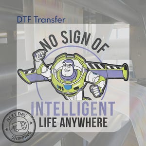 Puede incluir: Transferencia DTF con una imagen de dibujos animados de Buzz Lightyear y el texto "NO SIGN OF INTELLIGENT LIFE ANYWHERE". El dise&ntilde;o utiliza verde, blanco, morado y negro. Tambi&eacute;n hay un gr&aacute;fico circular con un cami&oacute;n y las palabras "NEXT DAY SHIPPING".