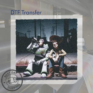 May include: A DTF transfer featuring a graphic illustration of two toy characters sitting on a curb at night. One character wears a white, green, and purple space suit, while the other wears a cowboy hat, yellow shirt, and blue jeans. The text DTF Transfer is visible.