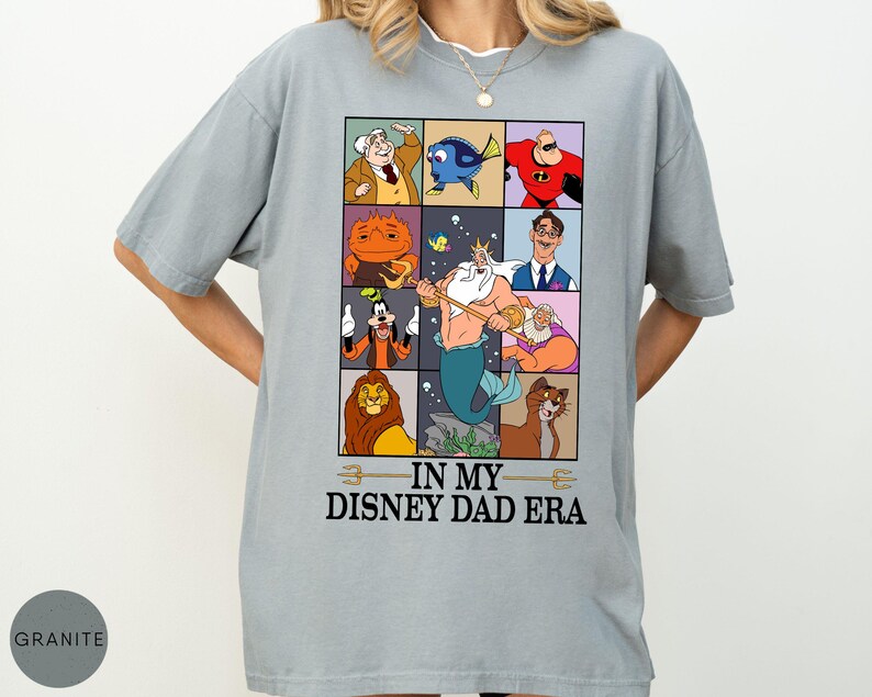 May include: A light gray t-shirt featuring a grid of Disney character illustrations. The shirt includes characters like Dory, Mr. Incredible, and Goofy. The text "IN MY DISNEY DAD ERA" is printed below the grid.