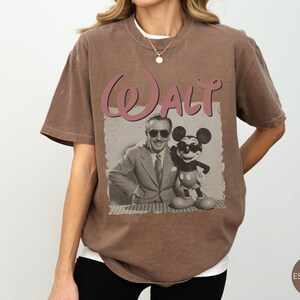 Puede incluir: Camiseta marr&oacute;n con un gr&aacute;fico vintage de Walt Disney y Mickey Mouse. La palabra "Walt" est&aacute; en una fuente de escritura sobre la imagen. La camiseta tiene un corte holgado y mangas cortas.