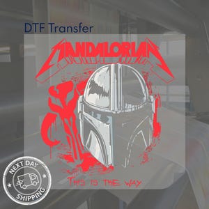 Op de afbeelding: Een rood-witte afbeelding met het woord "MANDALORIAN" in een gestileerd lettertype, met een helmontwerp en de zin "THIS IS THE WAY." De afbeelding is een DTF-transfer.