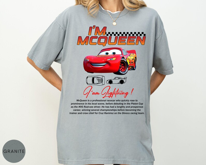 Puede incluir: Camiseta gris con un coche de carreras de dibujos animados rojo y el texto "I'M MCQUEEN". Debajo del coche, el texto "I am Lightning!" est&aacute; escrito en cursiva. La camiseta tambi&eacute;n tiene una descripci&oacute;n del coche.