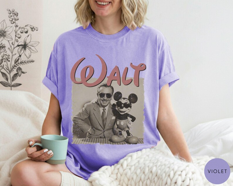 Puede incluir: Una camiseta violeta con un gr&aacute;fico vintage de Walt Disney y Mickey Mouse. El gr&aacute;fico est&aacute; en un marco rectangular con la palabra "Walt" en escritura rosa. La camiseta es de un estilo c&oacute;modo e informal.