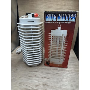 May include: A white bug zapper with a cylindrical design and a red and black power connector. The box next to it reads "BUG KILLER" and "OPERATED BY 12 VOLT CAR BATTERY".