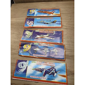 May include: Five vintage toy airplane packages. Each package features a different airplane design in various colours, with text that reads "WORLD AIRPLANE SKILL PERFORMANCE" and "CAN BE ROTARY TWICE IN THE AIR".