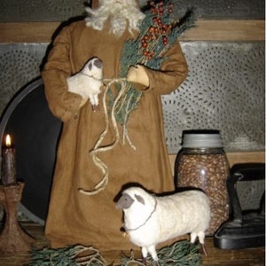 Peut inclure: Un Père Noël en feutre marron tenant une branche de verdure avec des baies rouges et deux agneaux en feutre blanc. La poupée a une barbe blanche et une capuche en feutre blanc.